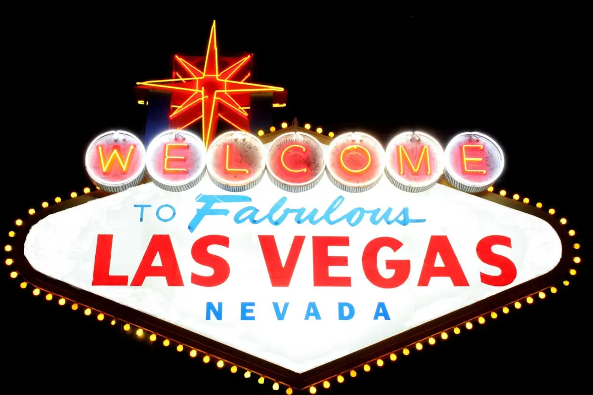 The iconic "Welcome to Fabulous Las Vegas, Nevada" sign, brightly lit against a black background. The sign features bold red, white, and blue letters, with circular lights along the top and a neon star at the top center. Image by Rya Eisma of Shamelessly Sexy Boudoir Photography, Las Vegas, NV